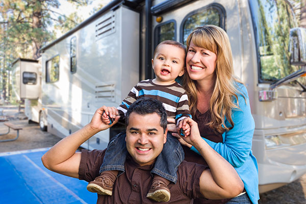 Happy young family in front of their new motorhome after thorough rv inspection services 